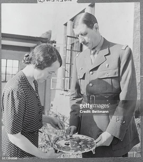 Prophet in Exile. Emblems: The General and his lady are looking over some of the military emblems and insignia is in the Fighting French Navy. The...