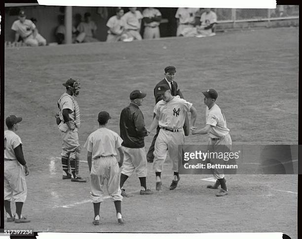 Yank pitcher Ed lopat and second baseman Gil Mcdouglad congratulate Mickey Mantee as he scores after them on his homer in the 7th inning of the game...