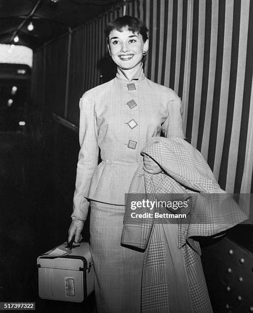 Lovely British actress Audrey Hepburn lights up with a charming smile as she leaves the Queen Mary, October 4, upon her arrival from England. Miss...