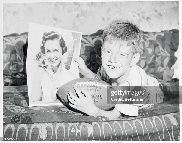 Thanks his lucky star...Smiling proudly over his brand-new football, and a picture of screen star Debbie Reynolds, 7-year-old Ritchie Schreiber is a...