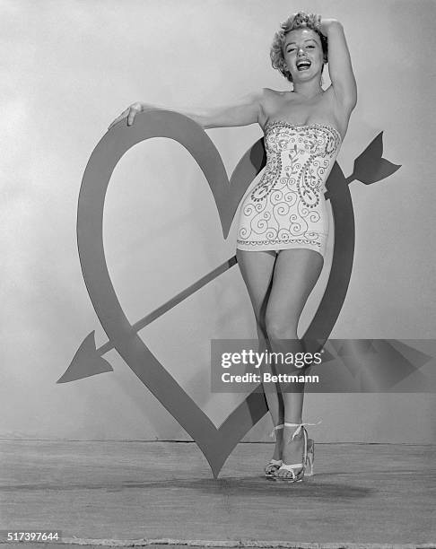Marilyn Monroe stands beside a large heart shape with an arrow through it for Valentine's Day.