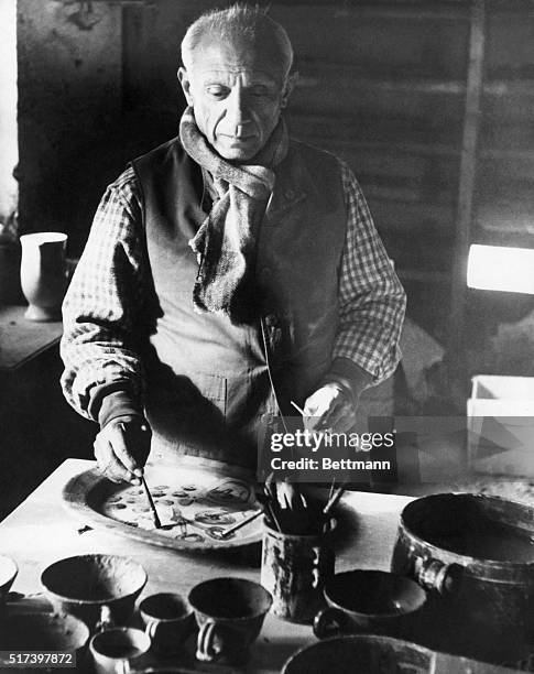 Pablo Picasso is shown painting decorations on a plate in his pottery studio at his villa on the French Riviera, 1948.