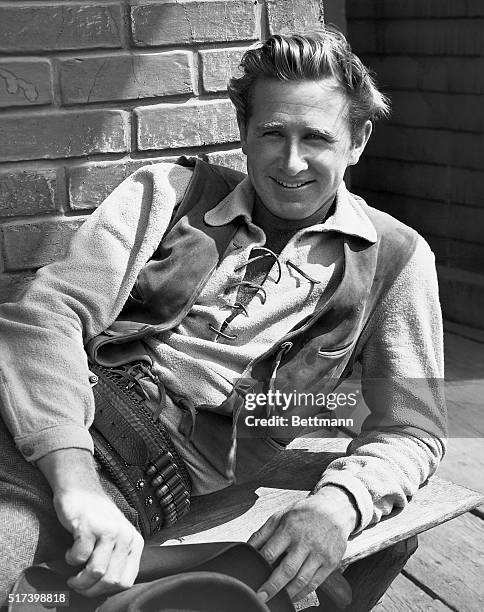 Picture shows Lloyd Bridges lounging on the set of the Hollywood Western film, "High Noon." Bridges is leaning back on one elbow, with cowboy hat in...