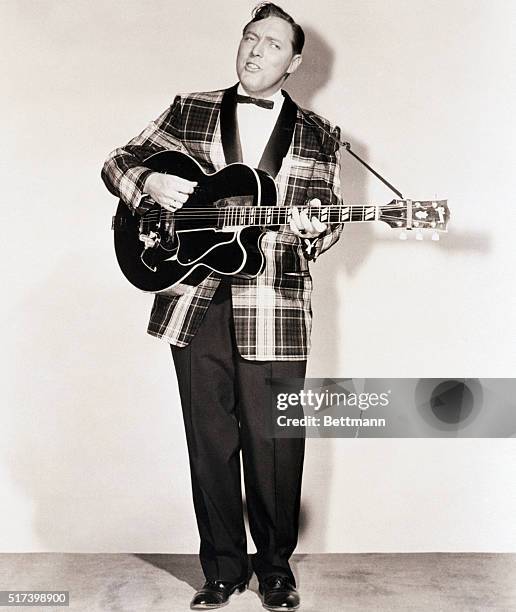 Publicity portrait of Decca recording artist Bill Haley. He is shown full-length, playing guitar and singing.