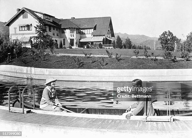 Famous Hollywood couple, Douglas Fairbanks and wife Mary Pickford, canoe along the swimming pool at their Pickfair estate.