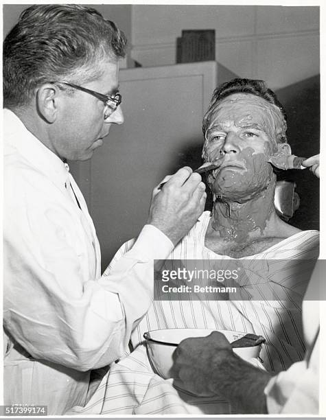 Actor, Charlton Heston, is shown with a plastic cast being applied to his face for his role in, "Ben Hur".