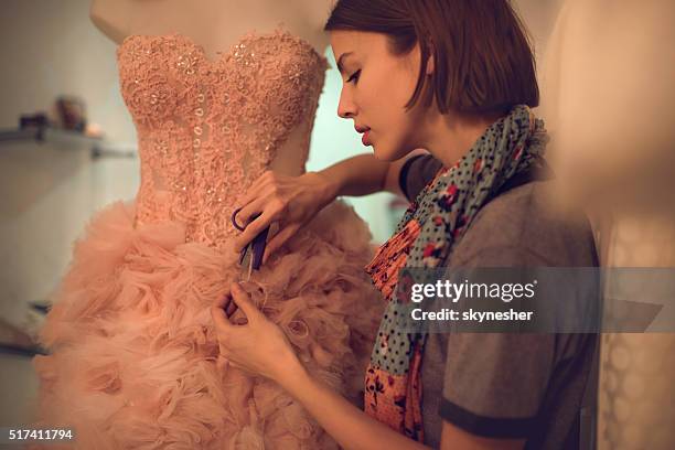 clothing designer cutting material on a dress in workshop. - dummy fashion stockfoto's en -beelden