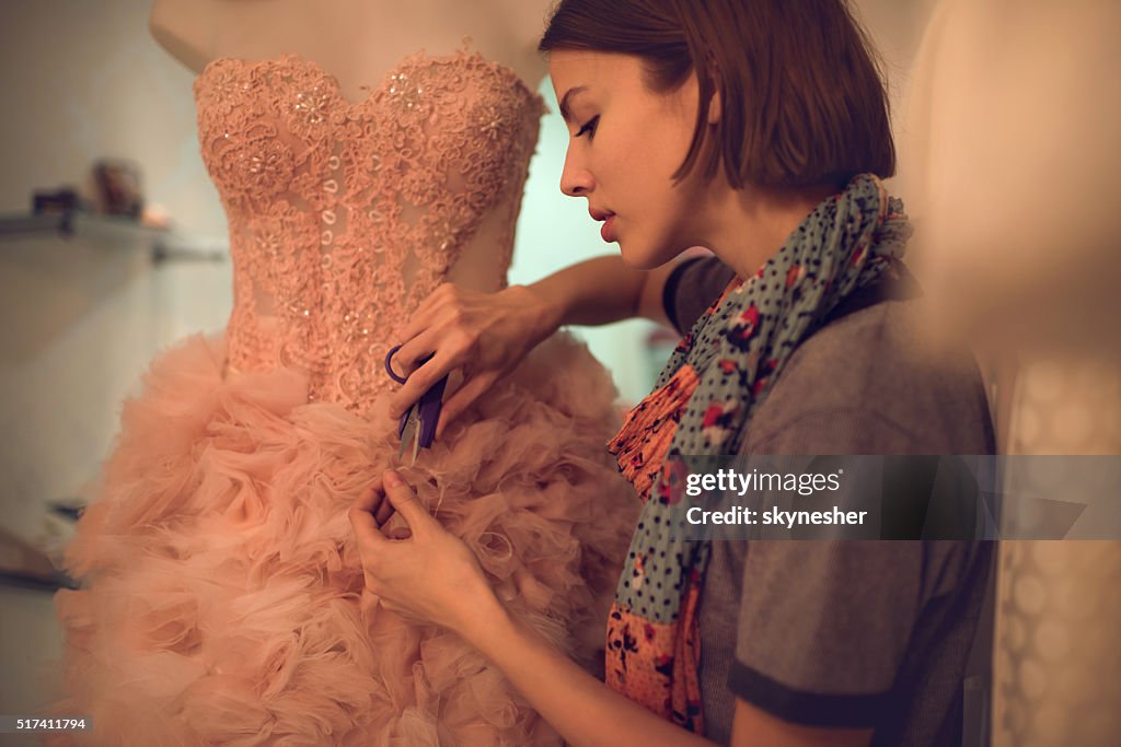 Vestuário Designer de material de corte em um vestido em curso.