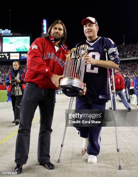 Boston Red Sox players Johnny Damon and pitcher Curt Schilling show off the World Series trophy before the New England Patriots game against the...