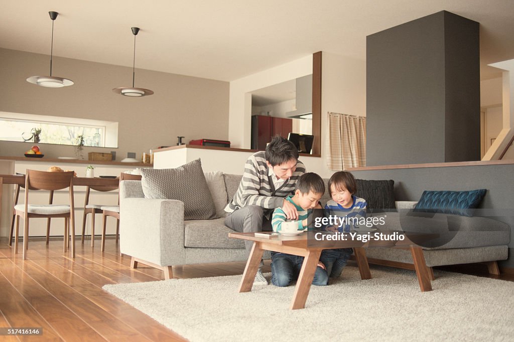 Father and two sons playing with a digital tablet together