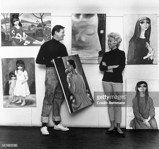 Artist Margaret Keane standing next to her painting: "Time in the Mind" ; her husband, Walter Keane holds his painting "We Will Overcome."