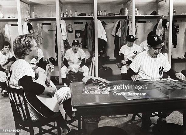Relaxing in the locker room, Tom Ligon strums guitar, Phil Foster plays cards and Hector Troy, Robert DeNiro and Michael Moriarty sit in background...