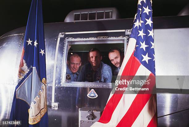 Space Center, Houston, Texas: The Apollo 11 astronauts, framed by an U.S. Air Force flag and the American flag, are shown upon arrival at Ellington...