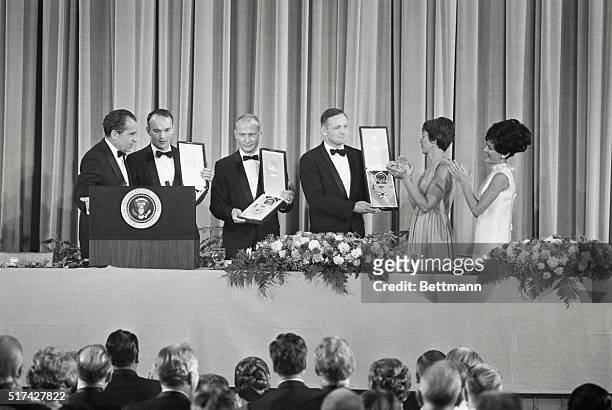 President Nixon presents Apollo 11 astronauts with the Freedom Award as two of their wives, Mrs. Armstrong and Mrs. Collins applaud. The astronauts...