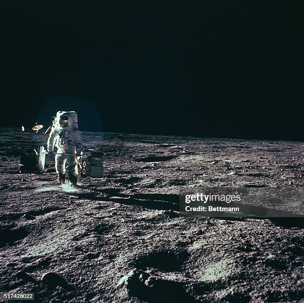 Space Center, Houston: An Apollo 12 astronaut carries ASLEP to deployment site on moon November 19th. He is carrying equipment in barbell fashion so...