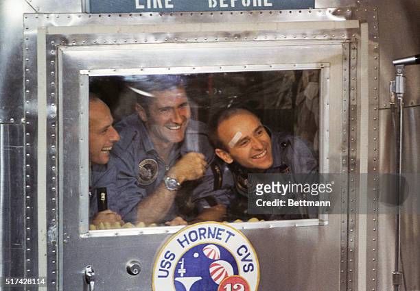 Aboard The USS Hornet - Safely aboard the carrier Hornet, Apollo 12 astronauts gin from the window of their Mobile Quarantine Facility. Left to...