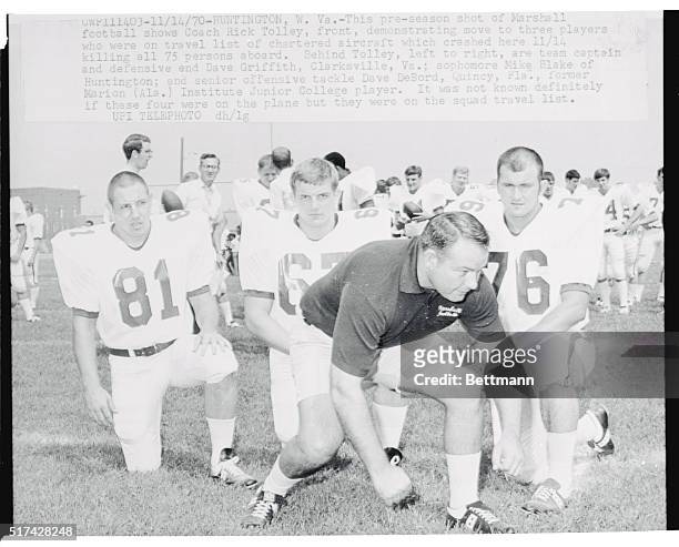 Huntington, W. Va.: This pre-season shot of Marshall football shows Coach Rick Tolley, front, demonstrating move to three players who were on travel...