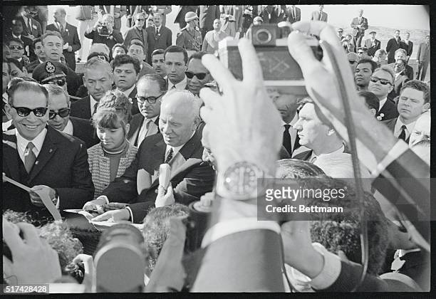 Aswan, Egypt: Soviet President Nikolai Podgorny and Egyptian President Anwar Sadat are surrounded by a crowd of dignitaries and newsmen as they cut...