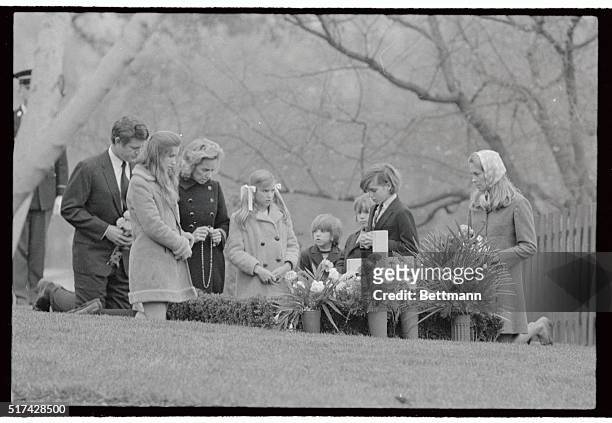 Mrs. Robert F. Kennedy, together with five of her children and Senator and Mrs. Edward Kennedy kneel at the grave of the late Senator Robert Kennedy...
