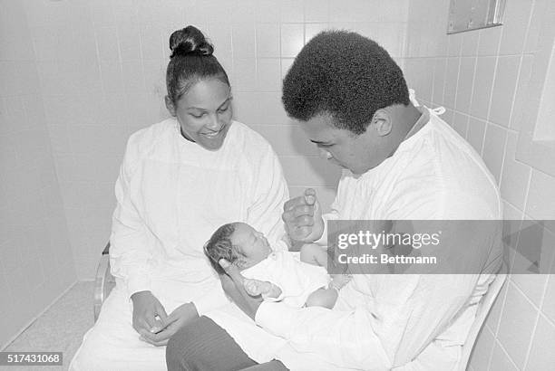 Boxer Muhammad Ali attempts to awake his firstborn son with a nudge towards his chin while his wife Belinda looks on at the hospital where the child,...