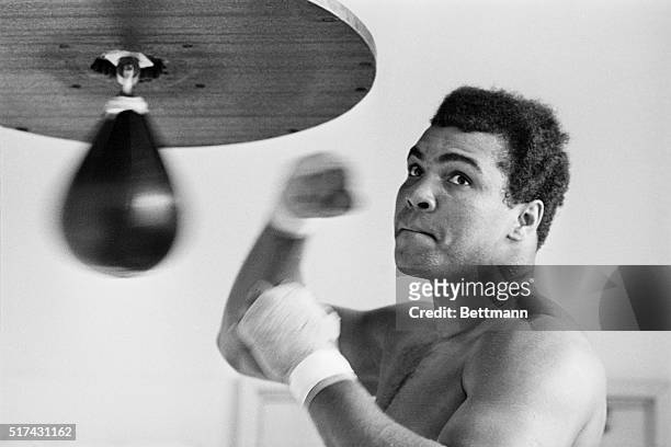 Caught in a rare pose- his mouth shut--Muhammad Ali punches bag here March 31 for his April 1 bout with heavyweight Mac Foster. The ex-champ predicts...