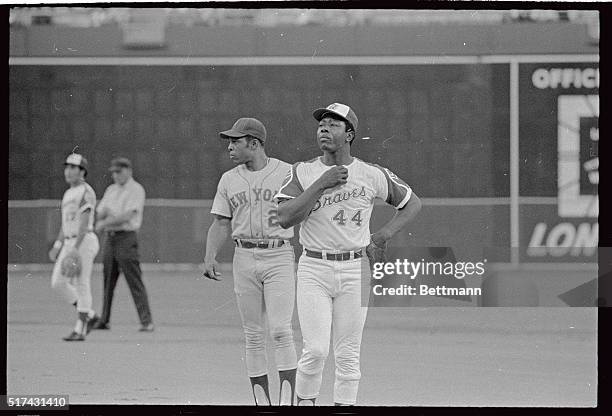 Braves super slugger Hank Aaron tugs at his collar as mets Willie Mays watches the Braves pitcher, Mays led off the first inning with a single and...