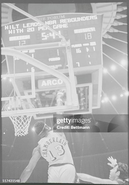 Inglewood, Calif.: With the scoreboard heralding his ability under his own basket, Wilt Chamberlain demonstrates his prowess under the other teams...