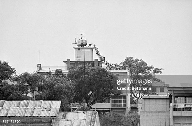 Employee helps Vietnamese evacuees onto an Air America helicopter from the top of 22 Gia Long Street, a half mile from the U.S. Embassy.