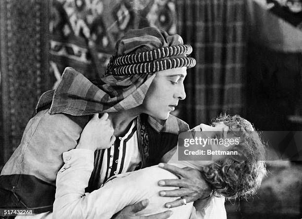 Rudolph Valentino holds Agnes Ayres in a movie still, publicity scene from the film "The Sheik".