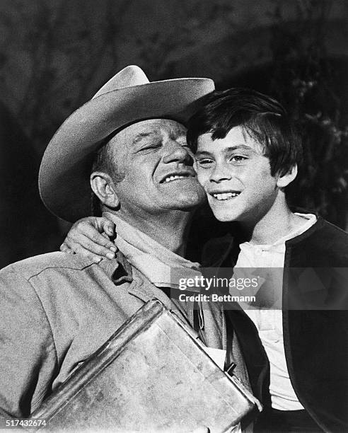 Hollywood, CA-: John Ethan Wayne gets a hug and some good words from Dad, John Wayne, after filming a shootout scene with outlaws in "The Million...