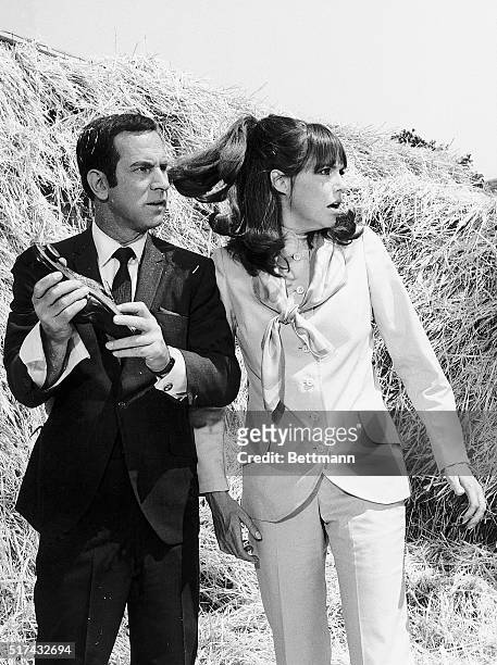 Agent 86 holds his shoe telephone as Agent 99 whirls in surprise, in the television spy comedy Get Smart.