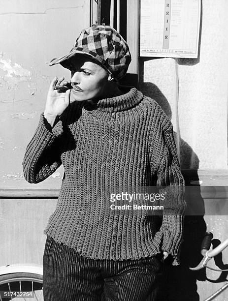 Jeanne Moreau with checkered cap, moustache, and smoking a stogie. She is dressed in drag. A scene from the 1962 French film, "Jules et Jim." Movie...