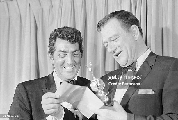 Hollywood, California-All smiles, actor John Wayne , reads a note after receiving the Cecil B. DeMille Award for "Outstanding Contributions to the...