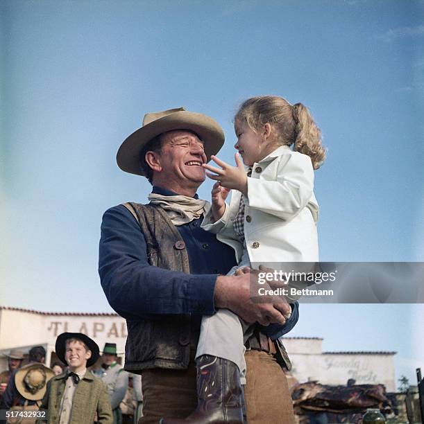 Hollywood, CA-: John Wayne holds his daughter, Aissa, on the set of "The Alamo."