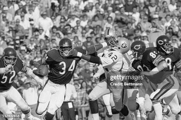 Chicago Bears' running back Walter Payton stiff arms Oakland Raiders corner back Monte Jackson as he makes a short gain on an end run in the second...