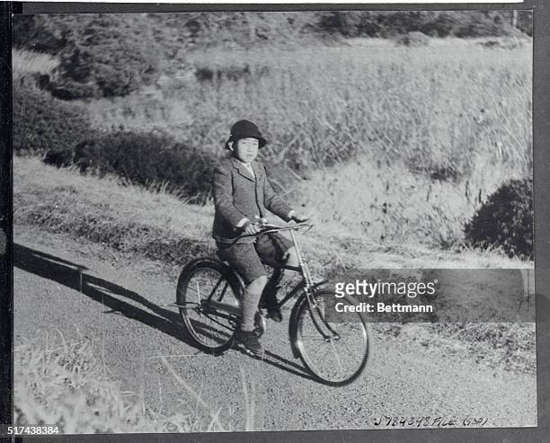 Crown Prince Akihito, heir to the throne of Japan, rides his bicycle on the palace grounds. This photo was made by the imperial household...