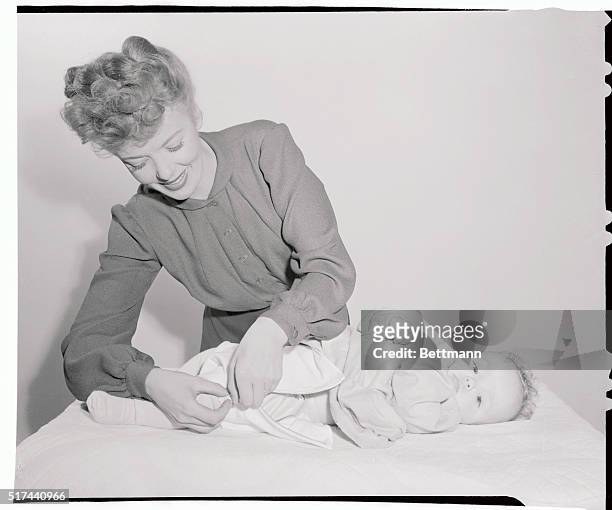 Calculated to meet infant emergencies with speed and precision, the zippered diaper is Hollywood's gift to postwar motherhood. Ida Lupino zips the...