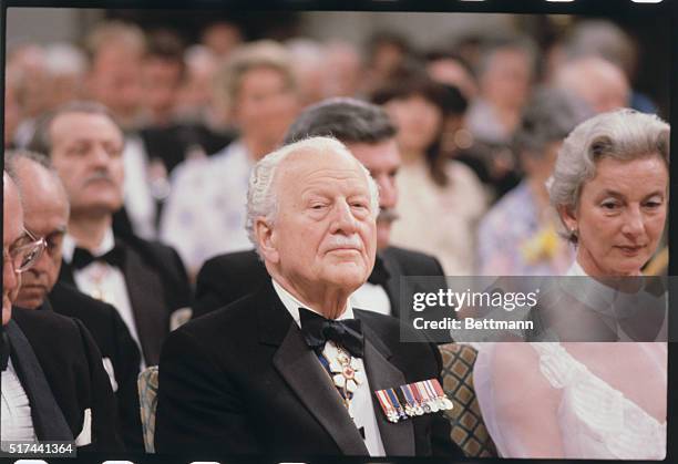 Wearing a tuxedo adorned with medals is the former Canadian governor general, Roland Michener.