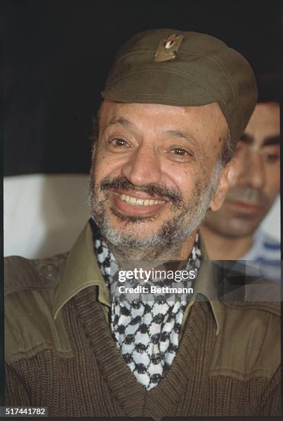 Tripoli, Lebanon: PLO Leader Yassar Arafat smiles during a press conference at PLO headquarters. He is wearing an olive-drab hat and a black and...