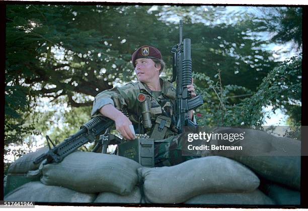 An MP, U.S. Army Specialist 4 Liz Milliken of California, holds an M-16 rifle with grenade launcher attached and rests her arm on am M-60 while...