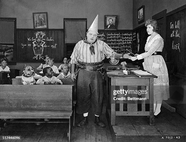 Fatty Arbuckle receives a punishment for his disobedience from his teacher while the other students watch in a scene from the 1918 comedy Out West.