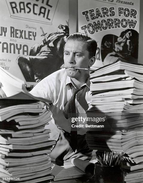 Movie still of Kirk Douglas struggling behind a desk full of scripts in "The Bad and the Beautiful," directed by Vincente Minelli.