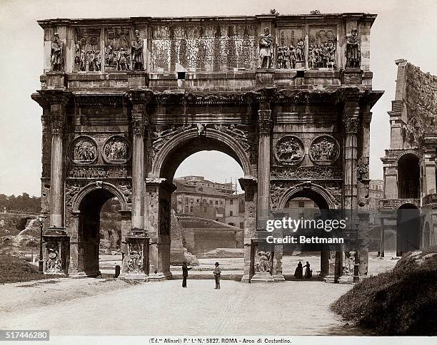 Rome, Italy. Undated view of the Arch of Constantine and side of the Colisseum, with passersby.