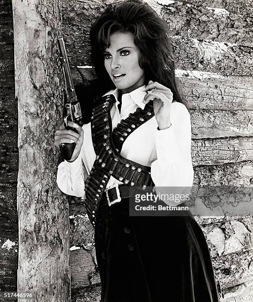 Photo shows Raquel Welch in a movie still, sporting a cowboy outfit and holding a large gun. "20th Century Fox presents "Bandolero!" Panavision....