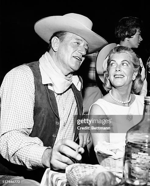 Big" John Wayne fully approved of the cowboy theme for the gigantic SHARE charity party. He exchanges gossip with Mrs. Gary Cooper, wife of the man...