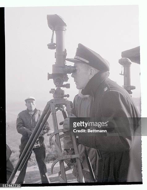 Admiral Arthur W. Radford, chairman of the U.S. Joint Chiefs of Staff, observes communist positions through periscope binoculars at a Korean...