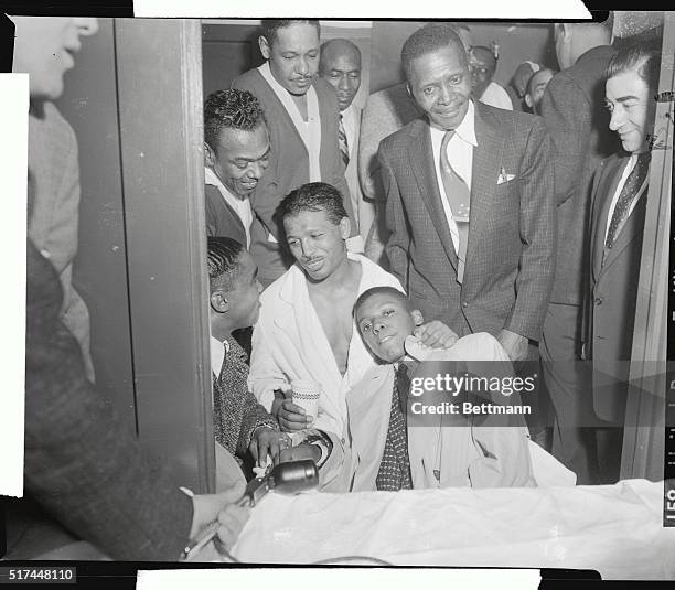Faint smile crosses face of Ray Robinson in dressing room as he is swarmed by well wishers after knocking out Carl Olson in 2nd round of their title...