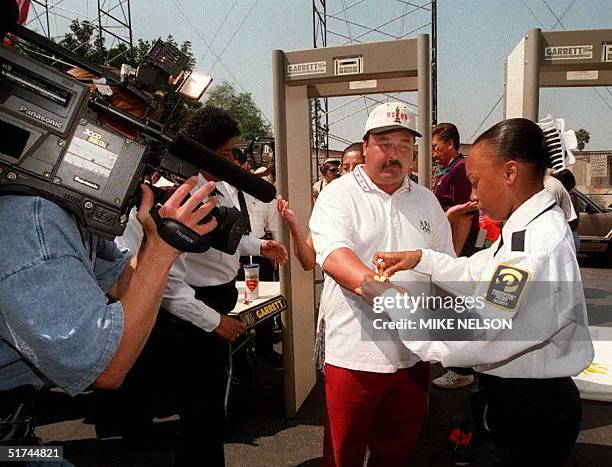 Frank Marquez is tagged by security guards after passing through a magnatometer and being hand scanned before he is allowed to find a seat in the...