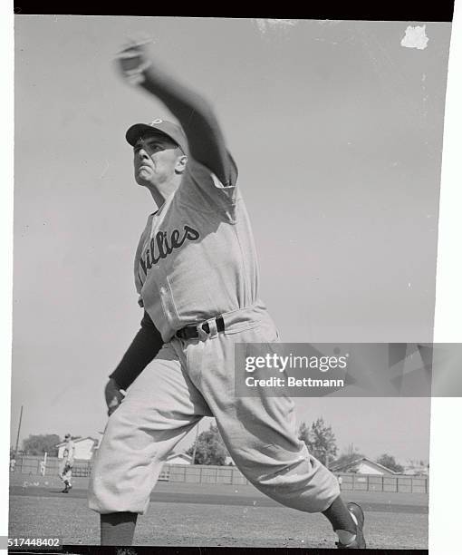 Philadelphia Phillies pitcher Curt Simmons in action on the mound at the Phillies' training camp. Simmons looks serious and determined as he starts...