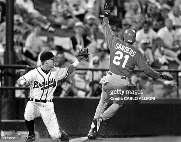 Jeff Blauser of the Atlanta Braves can't make the tag as Deion Sanders of the Cincinnati Reds waves while he steals third base in the first inning at...